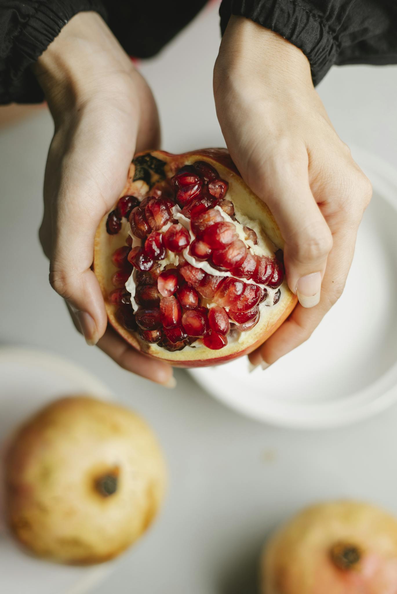 Woman having half of healthy ripe pomegranate